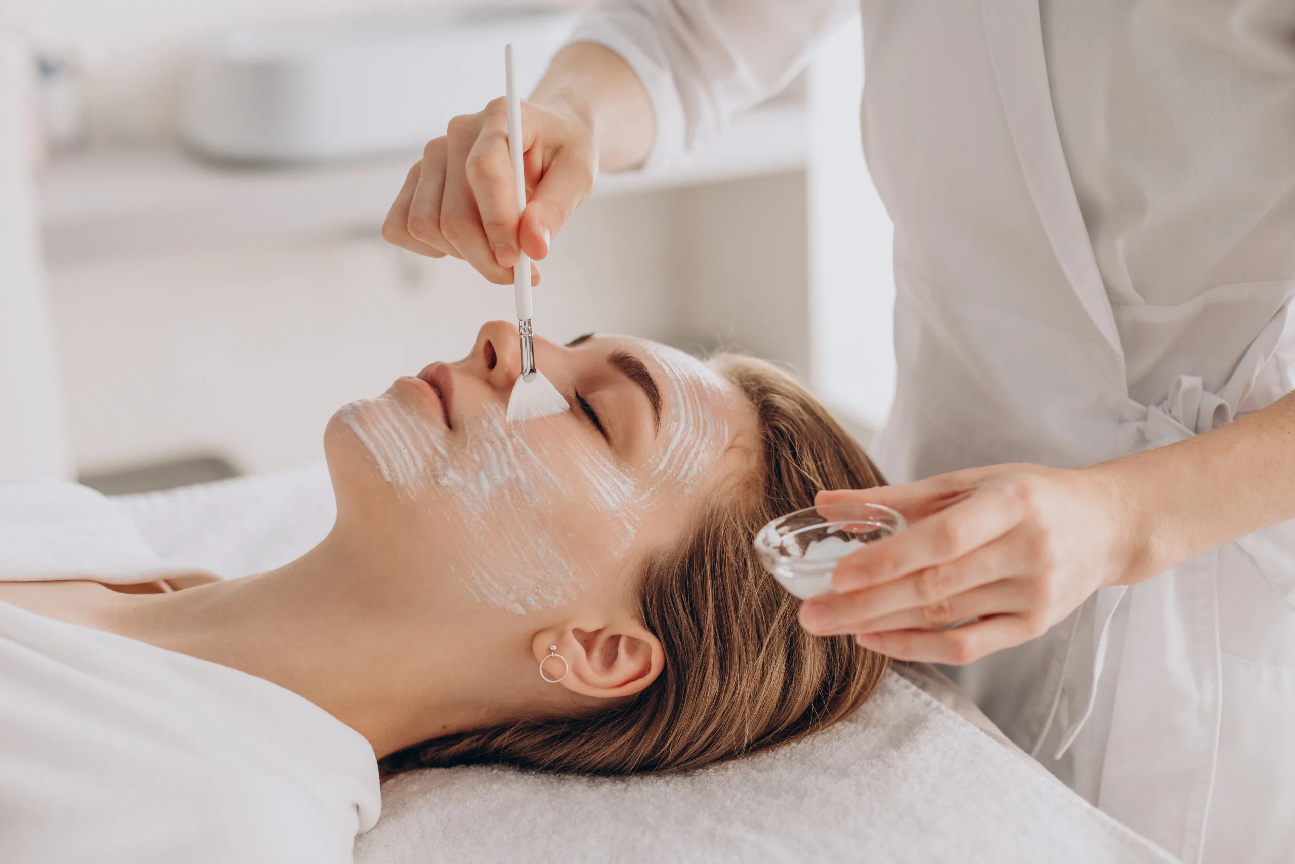 cosmetologista-fazendo-tratamento-facial-e-aplicando-mascara-facial-scaled